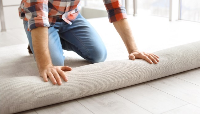 Man rolling carpet for installation | Carpetland USA